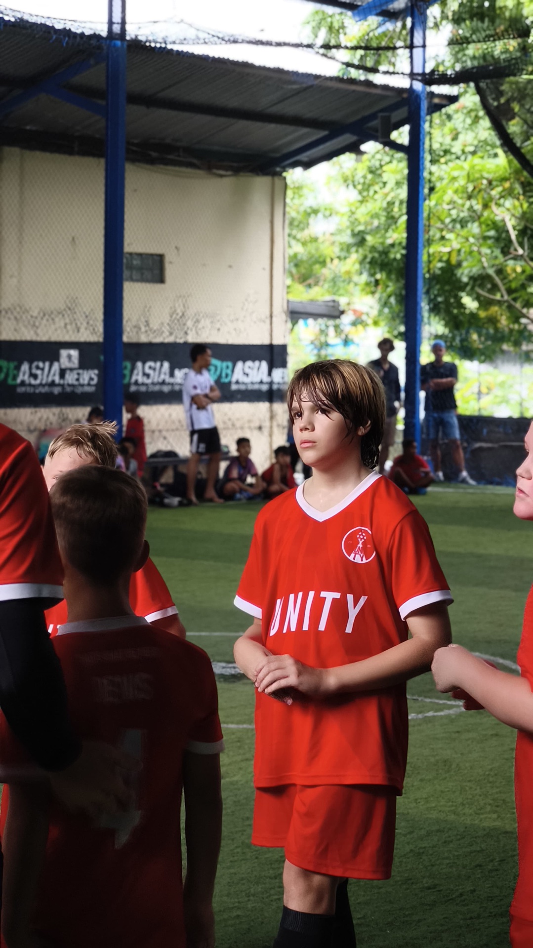 Older player in a red UNITY kit alongside teammates