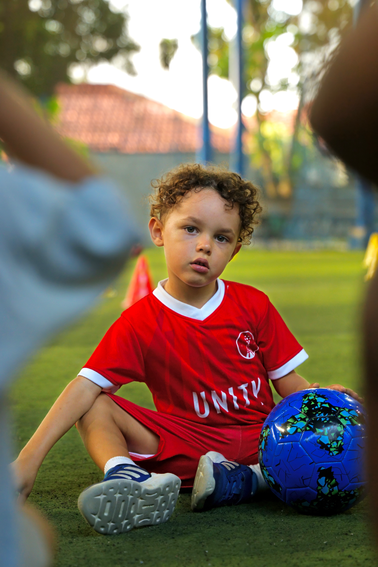 Young player in a red UNITY kit with a blue football