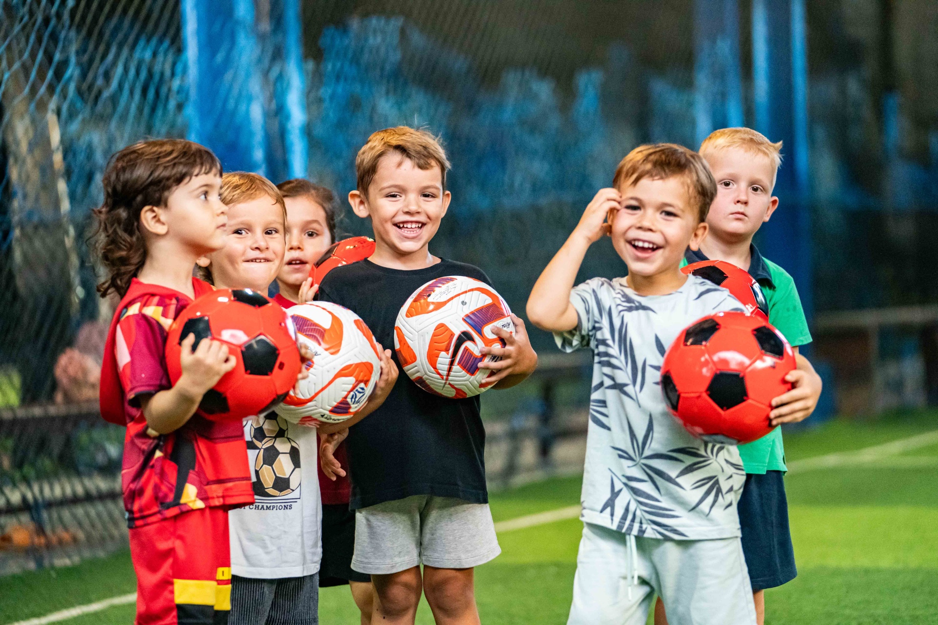 Smiling young footballers holding balls after training