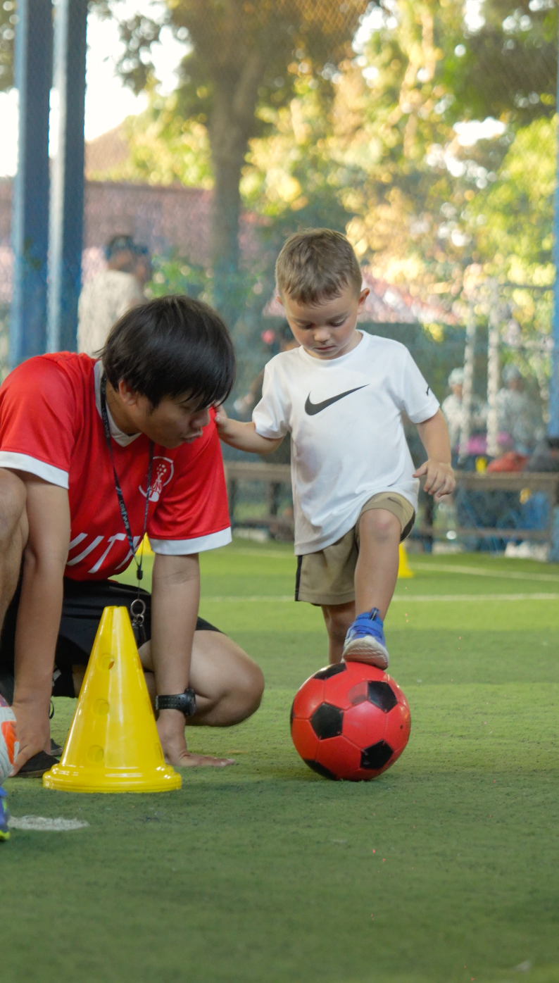 UNITY coach helping a child balance a foot on a football
