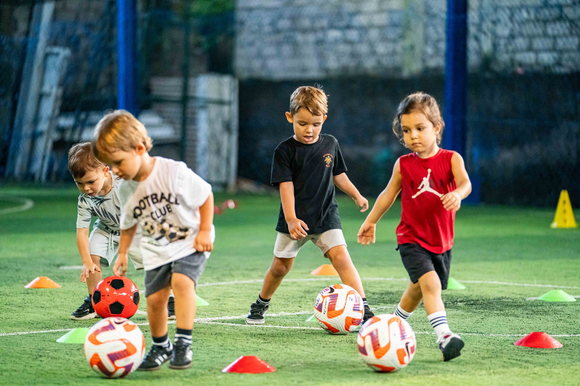 Children practising dribbling between colourful cones