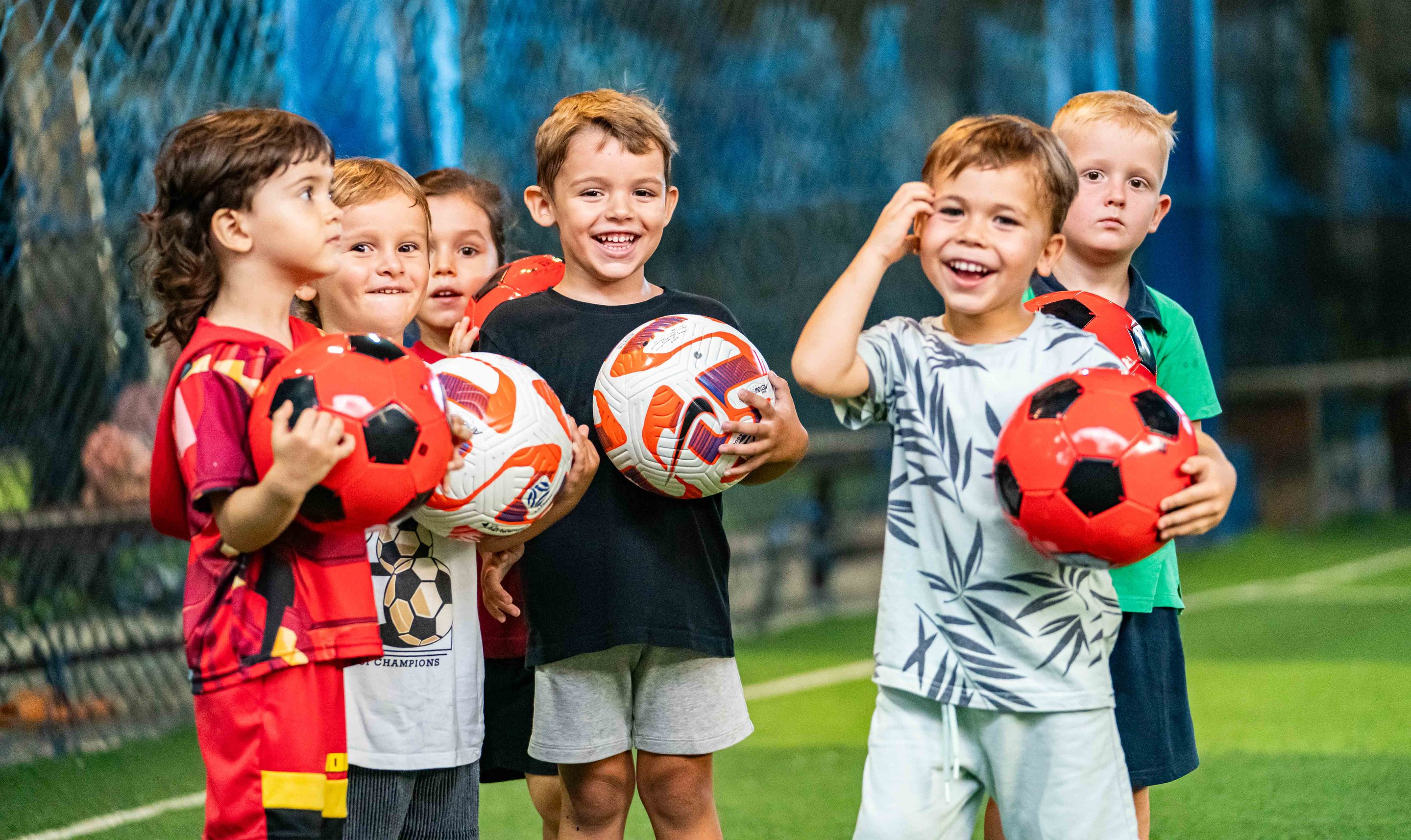 Children holding footballs together at UNITY Football Bali training